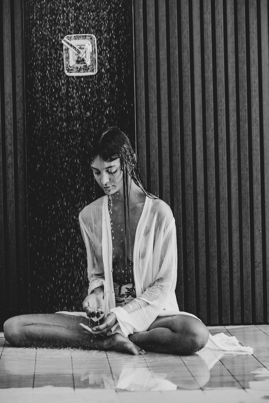 A woman sitting under an outdoor shower at our California desert resort.