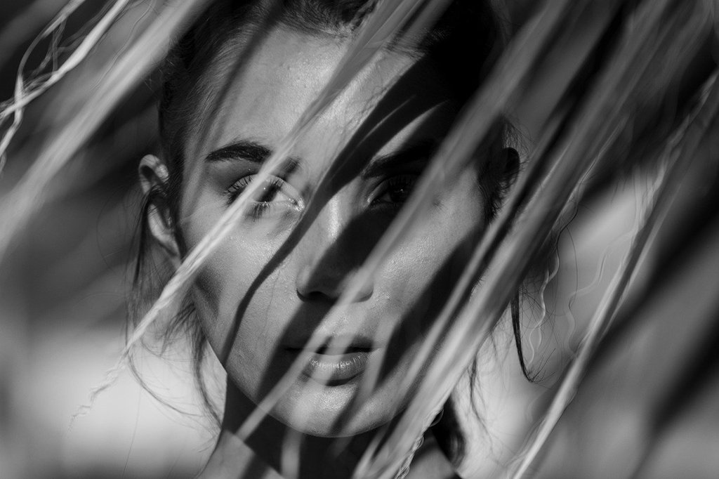 A woman looking through a palm leaf at our Palm Springs luxury resort.